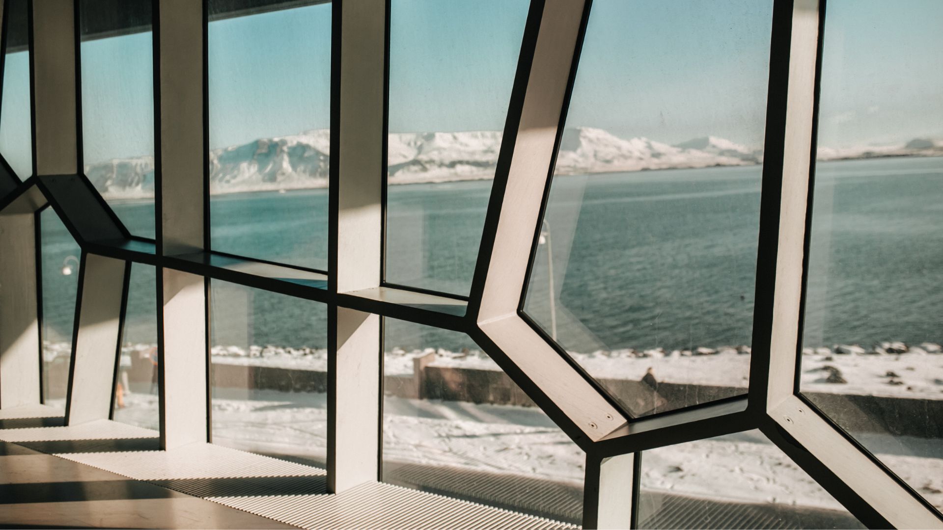 Large geometric windows with a view of a snowy lake.